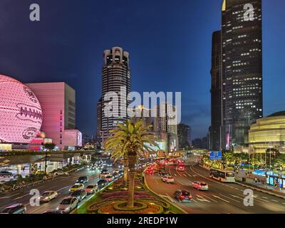 In der Gegend von Xujiahui ist viel Verkehr und es gibt einen erhöhten Fußweg mit dem Glassphärengebäude Metro City und den Wolkenkratzern von Grand Gateway bei Nacht Stockfoto