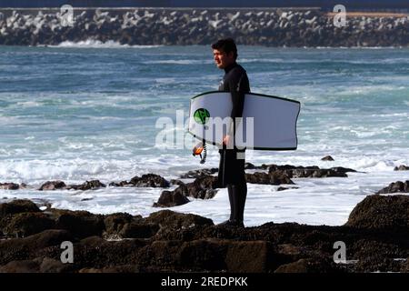 Bodyboarder auf Felsen mit Blick auf das Meer über dem Pazifischen Ozean, Arica, Chile Stockfoto