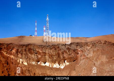Handy-/Funkmasten und Felsschichten auf dem Hügel der Wüste Cerro El Morro Gordo in der Nähe der Landzunge El Morro, in der Nähe von Arica, Chile Stockfoto