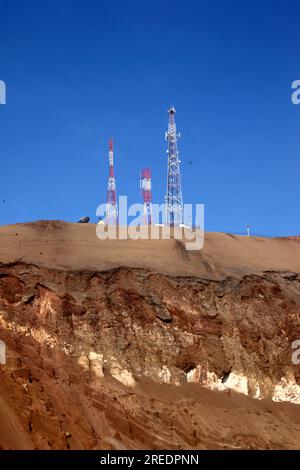 Handy-/Funkmasten und Felsschichten auf dem Hügel der Wüste Cerro El Morro Gordo in der Nähe der Landzunge El Morro, in der Nähe von Arica, Chile Stockfoto