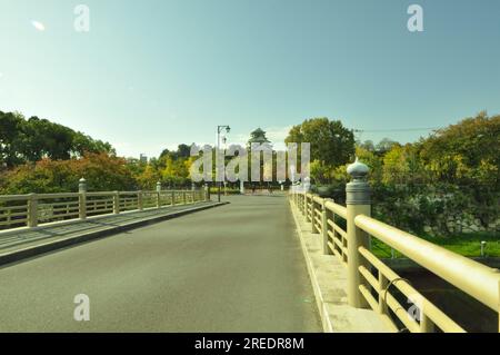 Malerische Reise durch Brücke und Landschaft mit Bäumen und Wolken vor dem Schloss Osaka Stockfoto