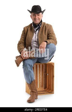 Reifer Cowboy, der auf weißem Hintergrund sitzt Stockfoto