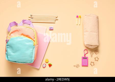 Stylischer Schulrucksack mit verschiedenen Schreibwaren auf orangefarbenem Hintergrund Stockfoto