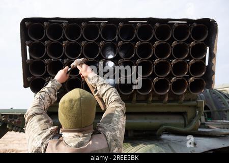 Soldat der ukrainischen Armee lädt ein Raketensystem BM-21 Grad während der Übungen auf dem Artilleriebereich in der Nähe des Dorfes Divychky, Kiew. Stockfoto