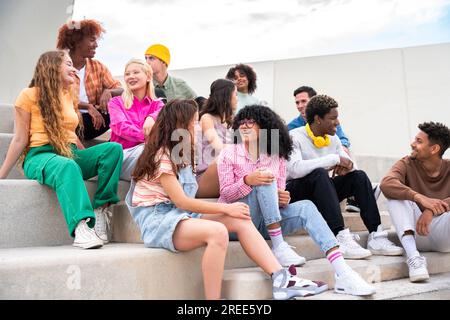 Fröhliche multiethnische Gruppe junger Freunde, die sich im Freien anfreunden - multiethnische Millennials Studenten, die sich in der Stadt treffen, Jugendkonzepte, Menschen li Stockfoto