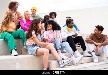 Fröhliche multiethnische Gruppe junger Freunde, die sich im Freien anfreunden - multiethnische Millennials Studenten, die sich in der Stadt treffen, Jugendkonzepte, Menschen li Stockfoto