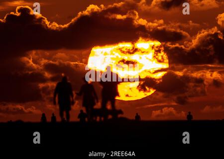 Isle Of Palms, Usa. 27. Juli 2023. Strandbesucher, die vom Sonnenaufgang über dem Atlantischen Ozean am Strand abgeschirmt wurden, 27. Juli 2023 auf der Isle of Palms, South Carolina. Eine anhaltende Hitzewelle über den Süden der USA bringt weiterhin extrem heißes, feuchtes Wetter in die Region. Kredit: Richard Ellis/Richard Ellis/Alamy Live News Stockfoto