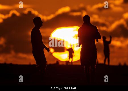 Isle Of Palms, Usa. 27. Juli 2023. Strandbesucher, die vom Sonnenaufgang über dem Atlantischen Ozean am Strand abgeschirmt wurden, 27. Juli 2023 auf der Isle of Palms, South Carolina. Eine anhaltende Hitzewelle über den Süden der USA bringt weiterhin extrem heißes, feuchtes Wetter in die Region. Kredit: Richard Ellis/Richard Ellis/Alamy Live News Stockfoto