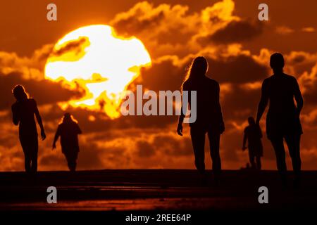 Isle Of Palms, Usa. 27. Juli 2023. Strandbesucher, die vom Sonnenaufgang über dem Atlantischen Ozean am Strand abgeschirmt wurden, 27. Juli 2023 auf der Isle of Palms, South Carolina. Eine anhaltende Hitzewelle über den Süden der USA bringt weiterhin extrem heißes, feuchtes Wetter in die Region. Kredit: Richard Ellis/Richard Ellis/Alamy Live News Stockfoto