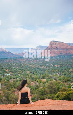 Frau genießt den Blick auf die Landschaft von Sedona von der Spitze des Bell Rock Wanderweges, der für seine vielen Energie-Wirbel und roten Felsen berühmt ist. Stockfoto