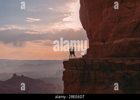 Silhouette von Frau und Mann auf dem Weg am Cathedral Rock bei Sonnenuntergang in Sedona. Der farbenfrohe Sonnenuntergang über Sedonas Cathedral Rock Wahrzeichen. Stockfoto