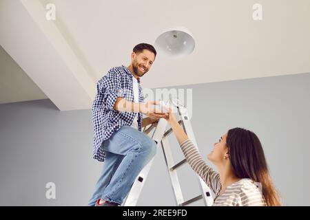 Lächelnder Mann, der zu Hause eine neue elektrische Glühlampe wechselt Stockfoto