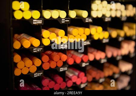 Selektiver Fokus auf helle, farbenfrohe Bleistifte in warmen Farben zum Zeichnen von Pastelltönen, die in einem Regal in der Kunstabteilung einer Schule zum Verkauf stehen Stockfoto
