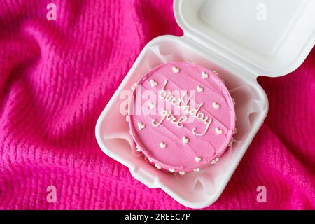 Wunderschöner, leuchtend rosafarbener Bento-Kuchen mit einer Inschrift auf pinkfarbenem Hintergrund. Die Inschrift auf dem Kuchen Geburtstagskind Stockfoto