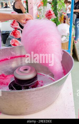 Eine Frau, die rosa Zuckerwatte an einem Straßenmarkt macht. Stockfoto