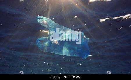 Blauer Einweg-Plastikbeutel schwimmt unter der Oberfläche in blauem Wasser bei Sonneneinstrahlung. Plastiktüte, die ins Meer geworfen wurde, treibt am Morgen unter der Oberfläche von blauem Wasser Stockfoto