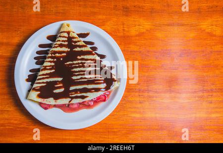 Crepe mit Schokoladencreme und Erdbeere auf einem Holztisch. Süße Erdbeercreme mit Schokoladencreme auf einem Holztisch Stockfoto