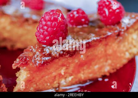 Nahaufnahme von hausgemachter Süßkartoffel, Kuchen mit Himbeeren und Kokosflocken auf einem roten Teller Stockfoto