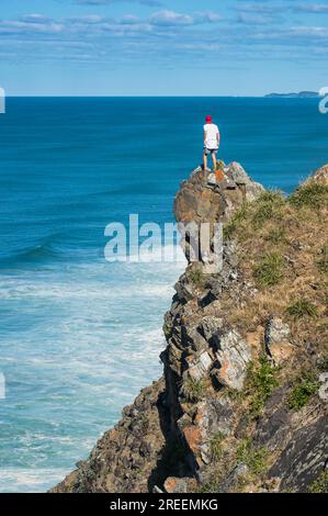 Mann sitzt auf einem Felsen auf den Klippen von Cape Byron, Byron Bay, Queensland, Australien Stockfoto