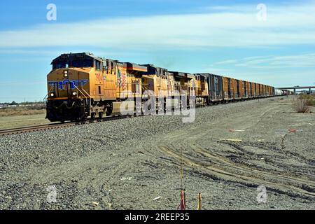 Drei Lokomotiven der Union Pacific Railroad fahren an der Kreuzung der 62. Straße in Indio California mit EINEM IN LA fließenden manifesten Güterzug an. Stockfoto