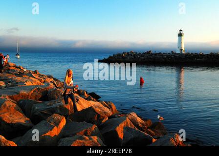 Eine junge Frau geht an einem sonnigen Sommertag auf einem Steg am Walton Lighthouse in Santa Cruz spazieren Stockfoto