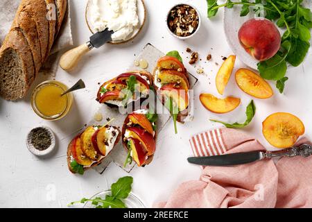 Toasts mit Frischkäse und gebackenen Pfirsichen, Rucola, Honig und Nüssen, Draufsicht Stockfoto