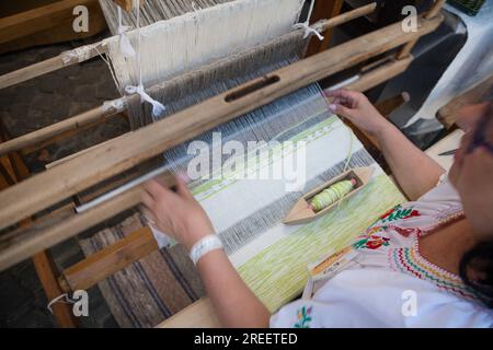 KEZMAROK, SLOWAKEI - 9. JULI 2023: Handwerkerin, die Baumwolle auf einem traditionellen Webstuhl aus Holz verarbeitet, beim European Folk and Crafts Festival in Kezmaro Stockfoto