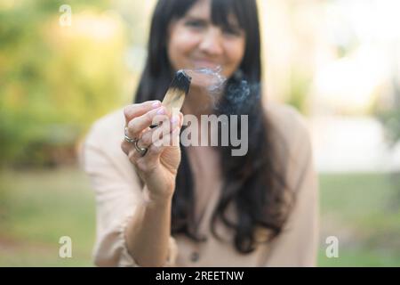Eine Frau mit langen Haaren, die einen brennenden palo santo oder einen heiligen Baum hält. Konzentrieren Sie sich auf den Vordergrund Stockfoto