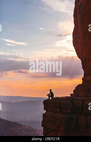 Silhouette des Menschen auf dem Pfad am Cathedral Rock bei Sonnenuntergang in Sedona. Der farbenfrohe Sonnenuntergang über Sedonas Cathedral Rock Wahrzeichen. Stockfoto