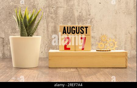 August. August 27 Holzwürfelkalender mit unscharfen Objekten auf dem Hintergrund. Stockfoto