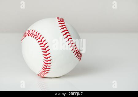 Nahaufnahme eines weißen Baseballballs mit roten Nähten auf weißem Hintergrund Stockfoto