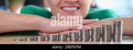 Lächelnde selbstbewusste Geschäftsfrau hat Münzen auf den Bürotisch gestapelt. Stockfoto