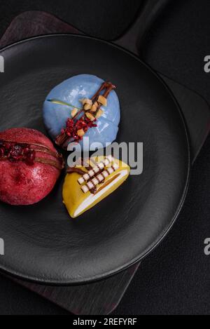 Köstliche süße bunte Mochi-Desserts oder Eiscreme mit Reisteig und Belägen auf dunklem Betonhintergrund Stockfoto