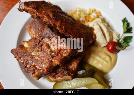 Rippchen in scharfer Marinade mit Chili, Honig, Sauerkohl, Gurke und Senf Stockfoto