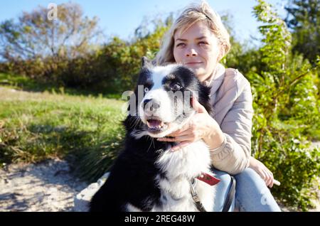 Besitzer mit einem sibirischen laika Hund am Strand. Freundschaft zwischen Hund und Frau Stockfoto