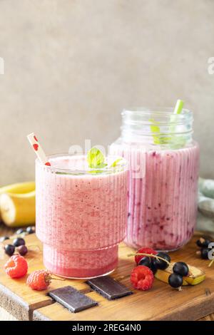 Set aus frischen, verschiedenen köstlichen Milchshakes oder Smoothies mit frischen Beeren auf rustikalem Hintergrund. Himbeeren und schwarze Johannisbeere. Speicherplatz kopieren. Stockfoto