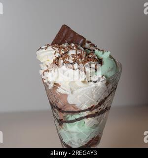 Minzgelateis in einem großen Eisbecher mit 3 Kugeln Eiscreme sowie verschiedenen Saucen und Belägen. Stockfoto