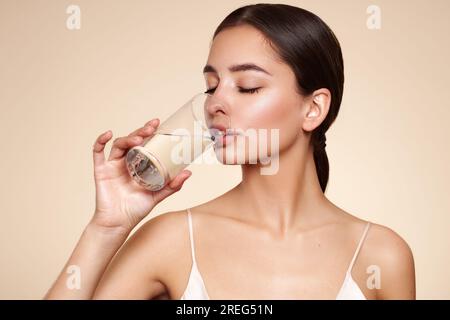 Junge, schöne Frau trinkt reines Wasser aus einem Glas. Gute Laune, gesunder Lebensstil. Stockfoto