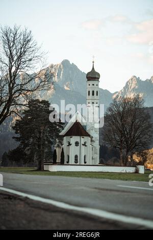 Blick auf St. Kolumanische Kirche in der Nähe von Schwangau am Herbstmorgen, Alpen im Hintergrund Stockfoto