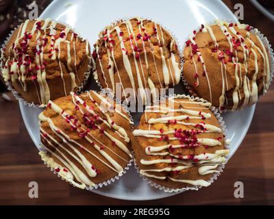 Himbeer- und weiße Schokoladen-Muffins auf weißem Teller Stockfoto