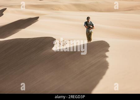 Der Mann geht mit seinem Hündchen entlang der windigen Sandkämme der Sanddünen Stockfoto