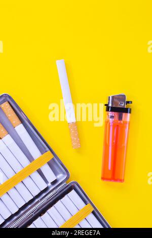 Zigaretten, Etui und Feuerzeug gegen Gelb Stockfoto