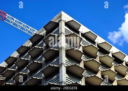 Betonbauecke. Mehrstöckige Hotelrahmenstruktur im Bau. Weiß-roter Kranausleger aus Stahlturm. Stockfoto