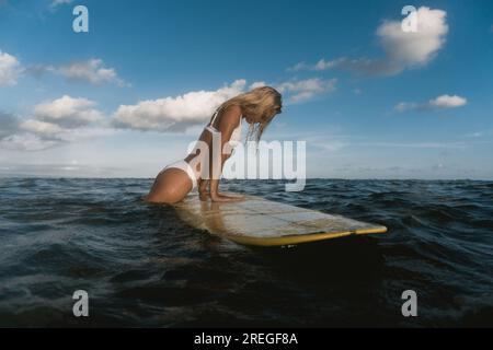 Eine Surferin auf einem Surfbrett im Meer, die auf die Wellen wartet. Stockfoto