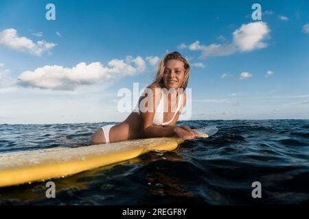 Eine Surferin auf einem Surfbrett im Meer, die auf die Wellen wartet. Stockfoto