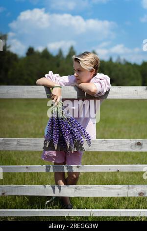 Eine junge Frau mit einem Strauß Lupinen auf dem Land. Stockfoto