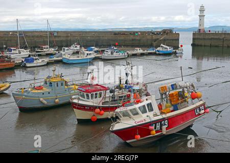 Fischerboote liegen bei Ebbe im Newhaven Harbour, Edinburgh, mit dem Hafenleuchtturm und Blick über den Firth of Forth in Richtung Fife Stockfoto
