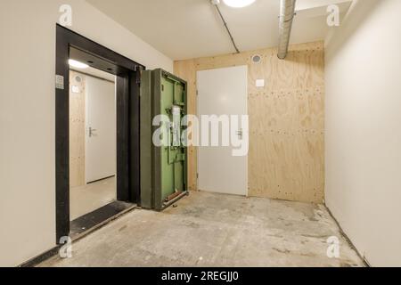Ein unfertiger Raum mit Holztäfelung an den Wänden und einer grünen Tür in der Wand wird installiert Stockfoto