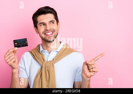 Foto eines attraktiven bärtigen Mannes Tragen Sie stilvolles Outfit Halt Plastikkarte Look up empty space cool Angebot isoliert auf pinkfarbenem Hintergrund Stockfoto