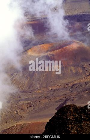 Weiße Wolken schweben über einem riesigen Aschekegel aus rotem Sand im riesigen vulkanischen Krater im Haleakala-Nationalpark auf Maui. Stockfoto